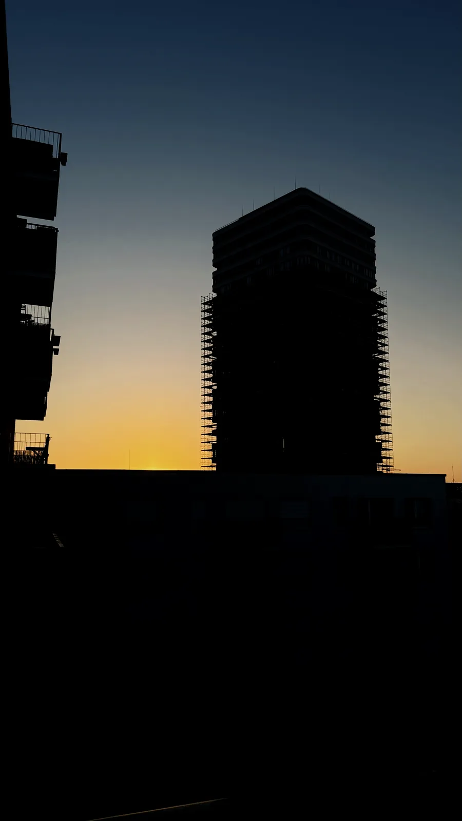 An apartment tower in silhouette against the dawn